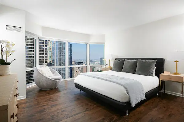 Bedroom with plush bed, dresser, city view window (One Hundred East Huron, Chicago) 