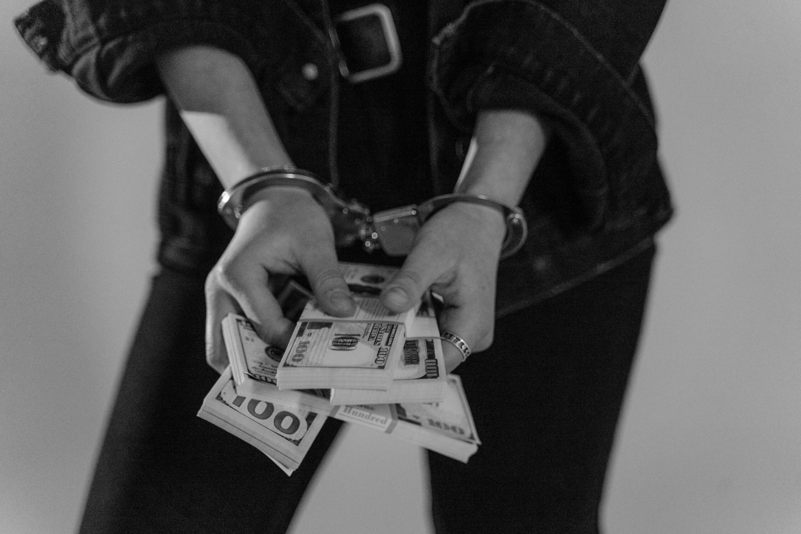 pair of hands in handcuffs, holding cash